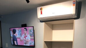 Ein Zimmer mit einem angebrachten Fernseher, einer integrierten Ablage mit Gläsern und einer Klimaanlage.