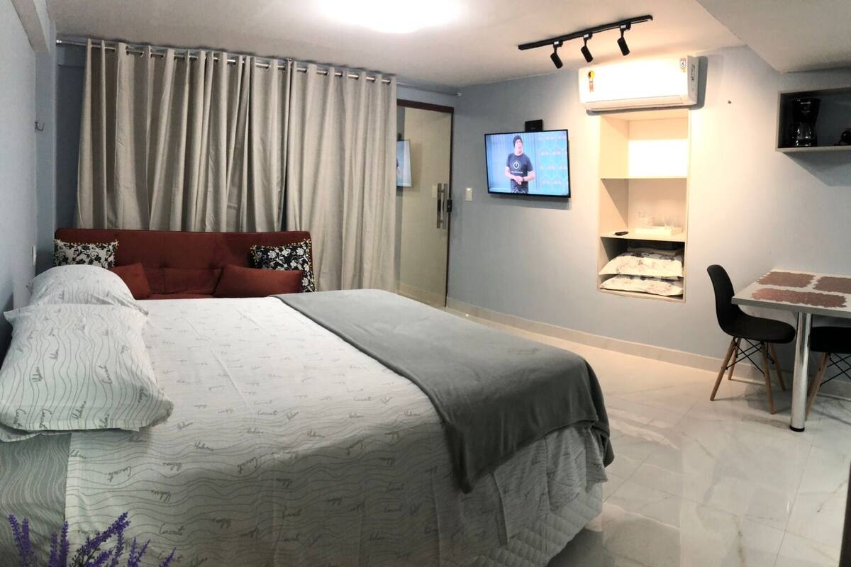 A hotel room with a bed, a TV, a coffee machine, and a dining table.