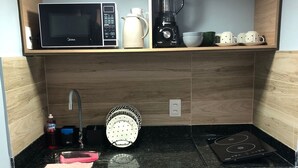 Eine kleine Küche mit Mikrowelle, Wasserkocher, Mixer und kleinem Kühlschrank.