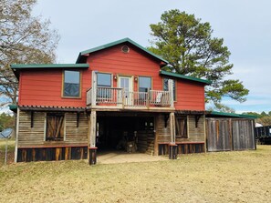 A two-story red building with a balcony, wooden siding, and a covered entrance. - Barnhouse @ Whiskey Flats Ranch (Palestine)