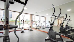 Una palestra con diverse cyclette e attrezzature per esercizi, ampie finestre e un design moderno e pulito.