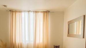 Un soggiorno con un divano marrone, un tavolo da pranzo apparecchiato con piatti, bicchieri e posate, e una finestra con tende leggere.