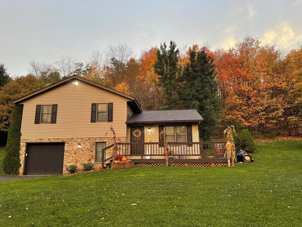 A two-story house with a stone foundation, a front porch, and a garage.
