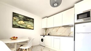 A modern kitchen with white cabinetry, a marble countertop, a washing machine, and a microwave. - Adas Nirvana, Heart of Los Cristianos (Los Cristianos)