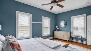 A bedroom with a bed, a dresser, a mirror, and a ceiling fan.