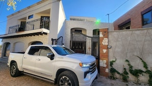 Un camionnette blanche était garée devant un immeuble à la façade en pierre, doté d’un balcon et d’une entrée fermée par un portail.