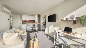 A modern apartment with a living area, a kitchen, a dining space, and a workspace.