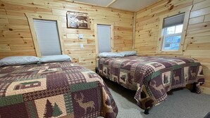 A cabin with two wooden beds, each with a quilt featuring animal patterns. - 
Cabin #3-New, Affordable, Year Round Lodging near Pictured Rocks & Tahquamenon! (Seney)