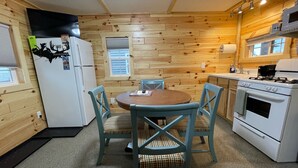 A compact kitchen with wooden walls, a round table, and four chairs. - 
Cabin #3-New, Affordable, Year Round Lodging near Pictured Rocks & Tahquamenon! (Seney)