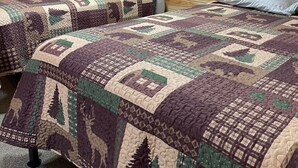 A cabin-style room with two beds, each with a quilted bedspread featuring forest and mountain designs. - 
Cabin #3-New, Affordable, Year Round Lodging near Pictured Rocks & Tahquamenon! (Seney)