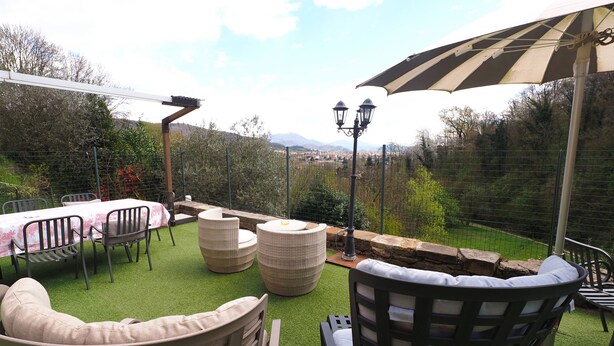 An outdoor patio with a table and chairs, a wicker sofa, and a large umbrella. - ☀️🌳🏡🦔Dimora del Riccio (Bergamo)