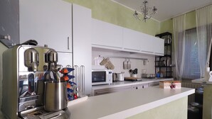 A modern kitchen with white cabinets, a stainless steel espresso machine, a microwave, and a sink. - ☀️🌳🏡🦔Dimora del Riccio (Bergamo)