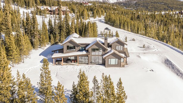 Een modern skigebied-lodge met meerdere gastenkamers, een skilift en uitzicht op de omliggende besneeuwde bergen.