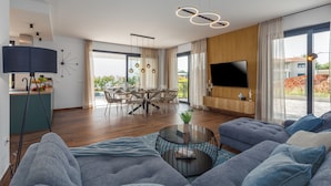 A modern living room with a large TV, comfortable seating, a dining area, and a view of the outdoors. - Villa Villa Mattia (Istria - Novigrad) (Novigrad)