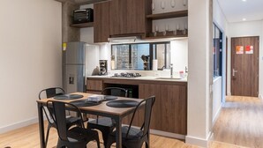 Una cocina moderna con armarios de madera, horno empotrado y comedor con mesa y sillas.