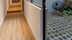 Un pasillo con suelo de madera que conduce a una habitación con un ventanal grande.