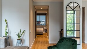 Ein modernes Interieur mit Holzboden, einem Samtstuhl in Grün und zwei Topfpflanzen.