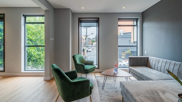 A modern living room with large windows, a grey sofa, and two green armchairs. - Bright 1BR @Zone G with Laundry (Bogotá)