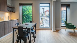 A modern kitchen with a dining area, large windows with city views, and a green chair. - Bright 1BR @Zone G with Laundry (Bogotá)