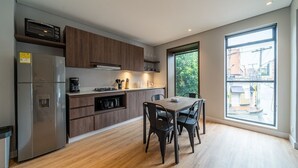 A modern kitchen with wooden cabinets, a stainless steel refrigerator, and a dining table with chairs. - Bright 1BR @Zone G with Laundry (Bogotá)