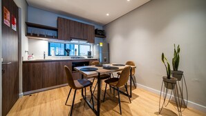 A modern kitchen with wooden cabinets, a built-in oven, and a dining table with chairs.