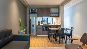Ett kompakt bostadsutrymme med ett litet kök, en matplats och sittmöbler.