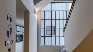 Interior moderno com escada, placa na parede e uma grande janela com padrão de grade.