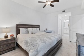 A bedroom with a bed, nightstands, a lamp, and a ceiling fan.