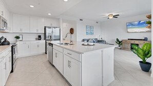 A modern kitchen with white cabinetry, a central island, and a ceiling fan.