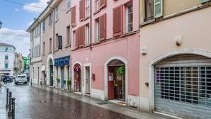 Rua com edifícios, calçada de pedras e porta de metal fechada.