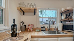 Eine Küche mit Holzarbeitsplatten, einer Edelstahlspüle und einem Fenster mit Blick ins Freie.