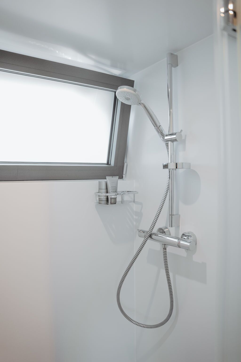 A modern shower with a handheld showerhead and a flexible hose.