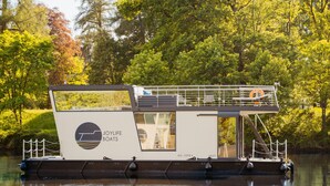 A stationary houseboat with a deck and a covered area, surrounded by trees and calm water. - Floating Home-Hausboot Saarschleife by Interhome (Mettlach)