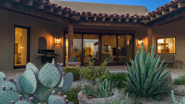 A house with a patio, a barbecue, and various cacti and succulents.