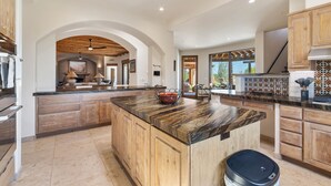 A spacious kitchen with wooden cabinets, a large island, and a view to the dining area.