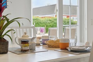 A breakfast table with a white teapot, a jar of jam, a basket of bread, and a cup of coffee. - Renovated summer house in Vejby/ Tisvilde (Vejby)