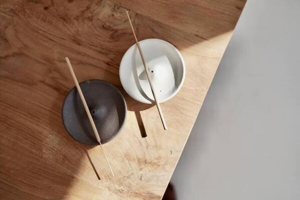Una mesa de madera con dos cuencos, uno negro y otro blanco, cada uno con un palito de madera.