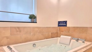 A modern bathroom with a large bathtub, a potted plant, and a sign reading "Avenue de Champagne". - Les Fauvettes (Épernay)