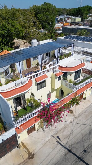 A multi-story building with balconies, solar panels, and a swimming pool. - Casa Bien Estar (Merida)