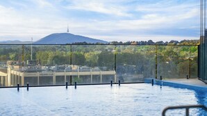 Une piscine à débordement offrant une vue dégagée sur une montagne et, au loin, sur le paysage urbain.