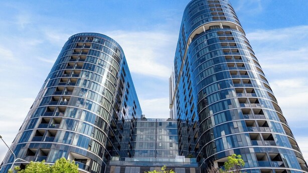 Un immeuble moderne de grande hauteur, doté d’une façade incurvée et de nombreux balcons.