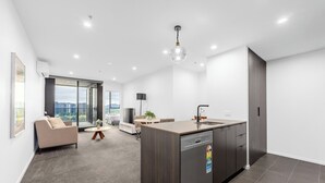 Un appartement moderne doté d’une cuisine, d’un espace de vie et d’un balcon offrant une vue sur la ville.