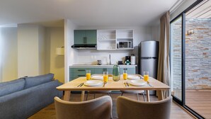 A modern kitchen with a dining area, a sofa, and a view of a stone wall. - Magis Downtown Juarez by Capitalia (Mexico City)