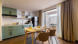 A modern kitchen with green cabinets, a dining area with a wooden table and chairs, and a large window with curtains. - Magis Downtown Juarez by Capitalia (Mexico City)