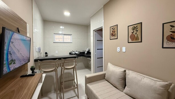 A modern kitchen with a dining area, a sofa, and a TV.