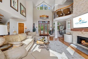 A spacious living area with a large sofa, a fireplace, and a staircase leading to an upper level.