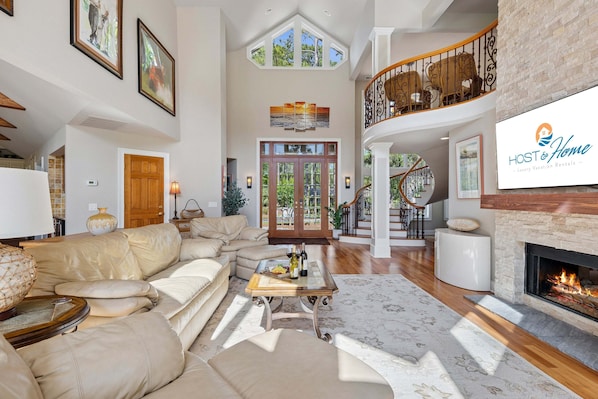 A spacious living area with a large sofa, a fireplace, and a staircase leading to an upper level.