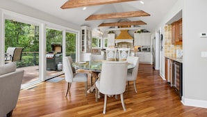 Una cocina amplia con vigas de madera, una mesa de comedor de cristal y vistas a una terraza.