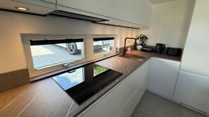 A modern kitchen with three windows, a built-in sink, and a coffee machine.