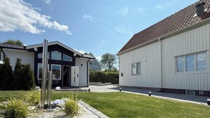 A modern two-story house with a well-maintained lawn and a small garden area.